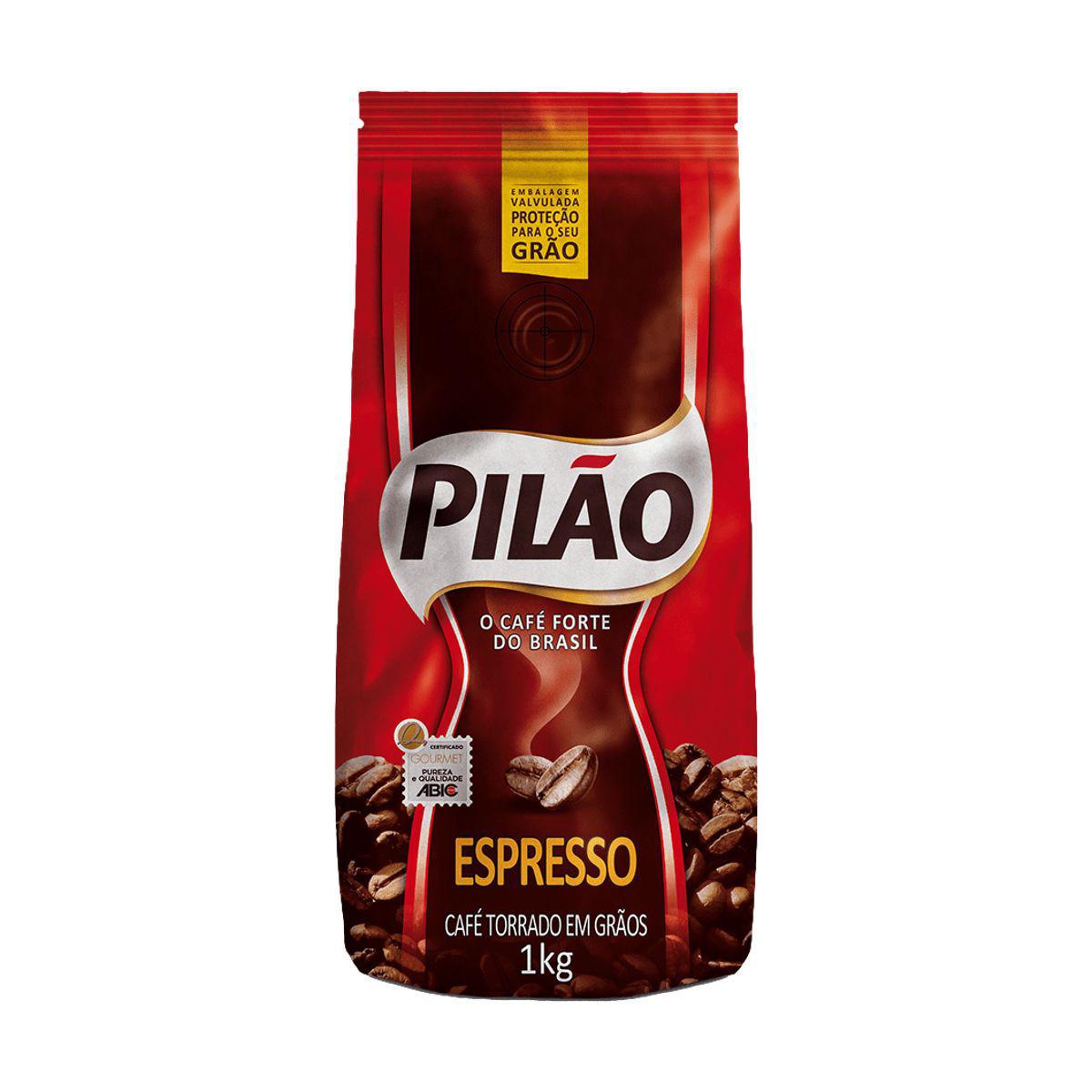 Pacote de café da marca Pilão, sabor Espresso. A embalagem é predominantemente vermelha e marrom, e apresenta grãos de café espalhados na parte inferior, indicando que é café torrado em grãos. O pacote tem 1kg e a frase 'O café forte do Brasil'.