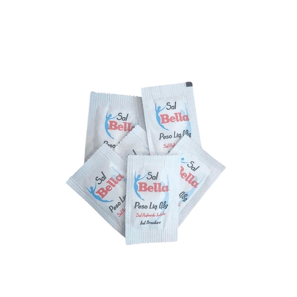Um punhado de sachês individuais brancos de Sal Bella com logo em azul e vermelho, espalhados uns sobre os outros. Cada sachê contém Sal Refinado Iodado com Peso Líquido de 0,8g.
